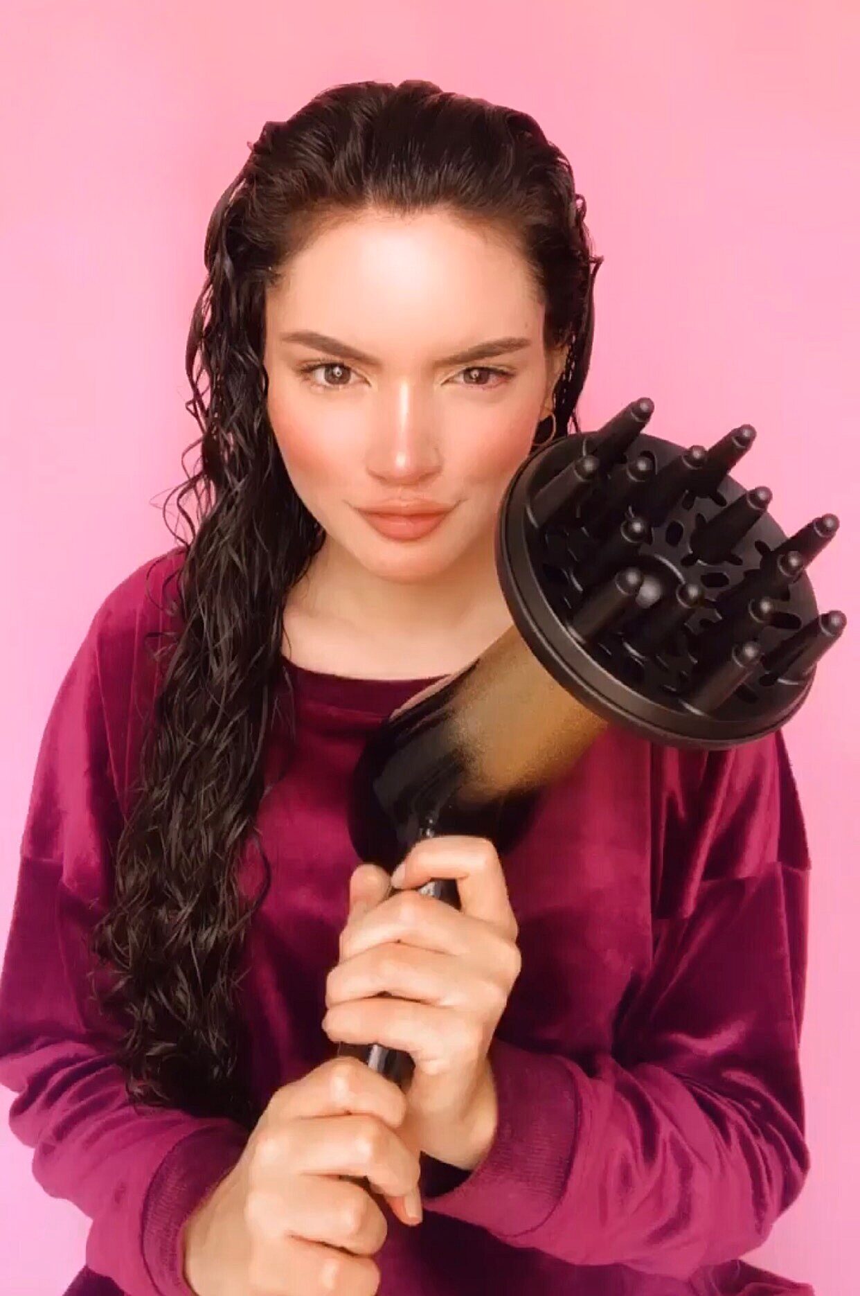 Una chica de cabello rizado con secador y difusor de aire después del  peinado